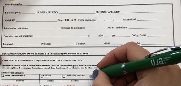 Una mano utiliza un bolígrafo para escribir sobre una solicitud